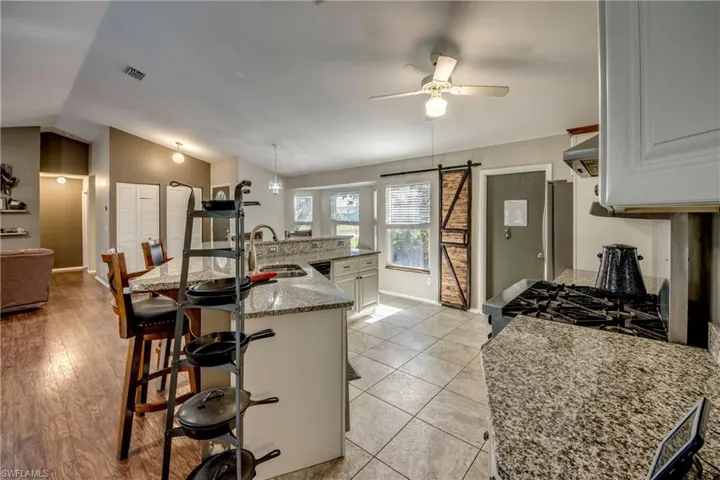 Kitchen with a sink, a kitchen breakfast bar, ceiling fan, lofted ceiling, and baseboards