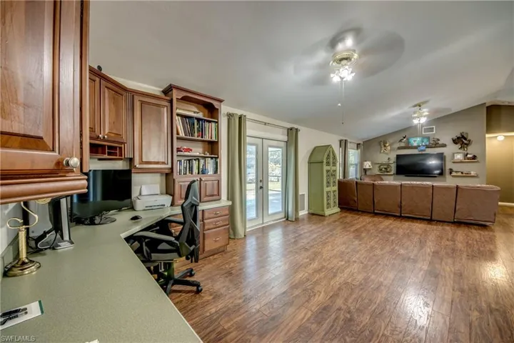 Office with a ceiling fan, wood finished floors, lofted ceiling, french doors, and baseboards