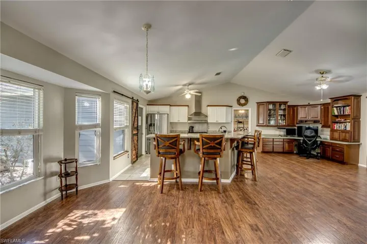 Dining room featuring a ceiling fan, vaulted ceiling, plenty of natural light, dark wood-style flooring, and baseboards