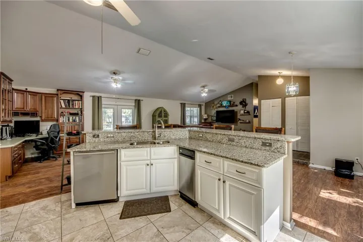 Kitchen featuring a sink, a ceiling fan, dishwasher, open floor plan, and lofted ceiling