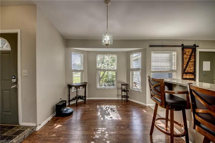 Dining space featuring dark wood-style floors, a barn door, and baseboards