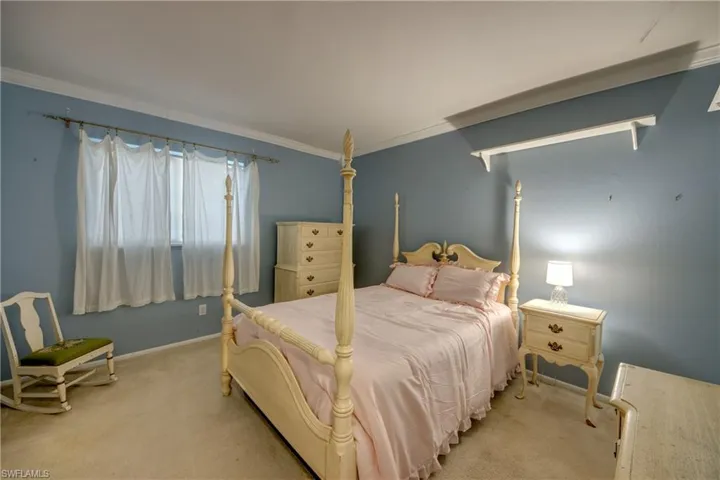 Bedroom with light carpet, crown molding, and baseboards