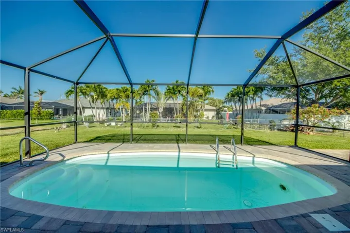 Swimming pool with glass enclosure, a lawn, and a residential view