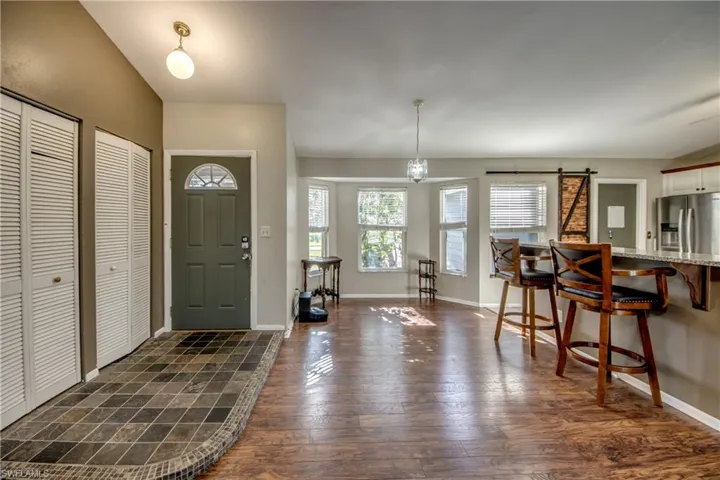 Foyer entrance with dark wood finished floors, a barn door, and baseboards