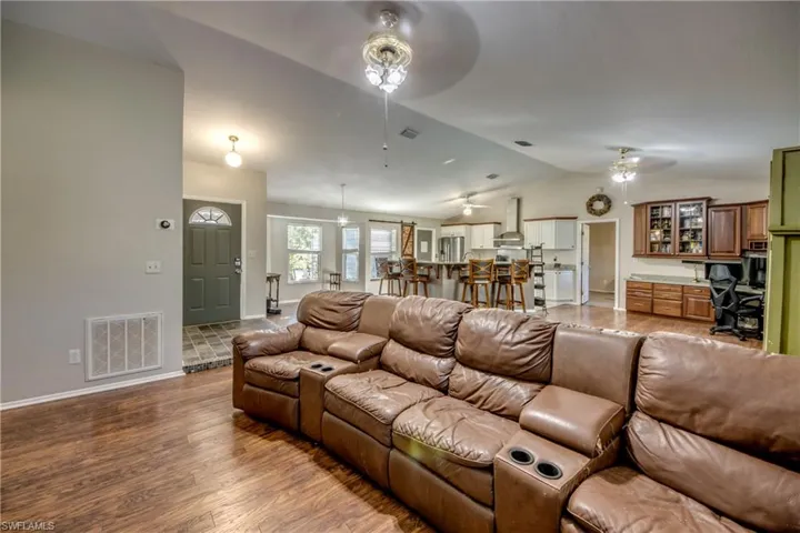 Living area featuring ceiling fan, lofted ceiling, baseboards, and wood finished floors