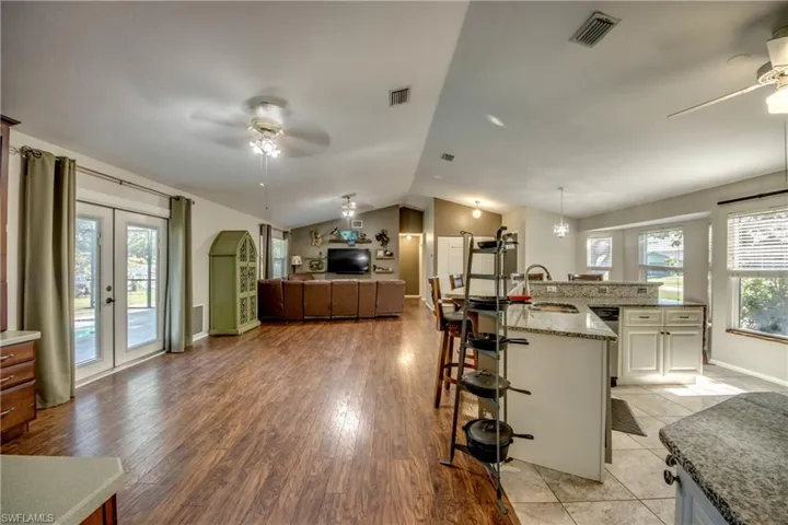Kitchen featuring ceiling fan, a breakfast bar area, a sink, lofted ceiling, and light stone counters