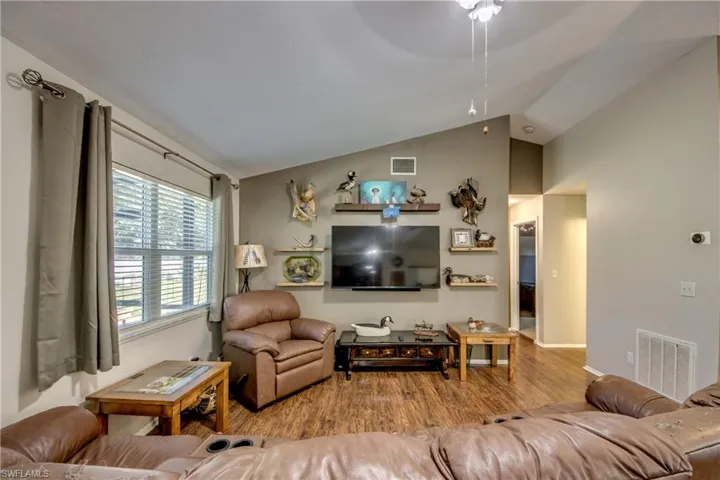 Living room featuring wood finished floors, ceiling fan, and vaulted ceiling