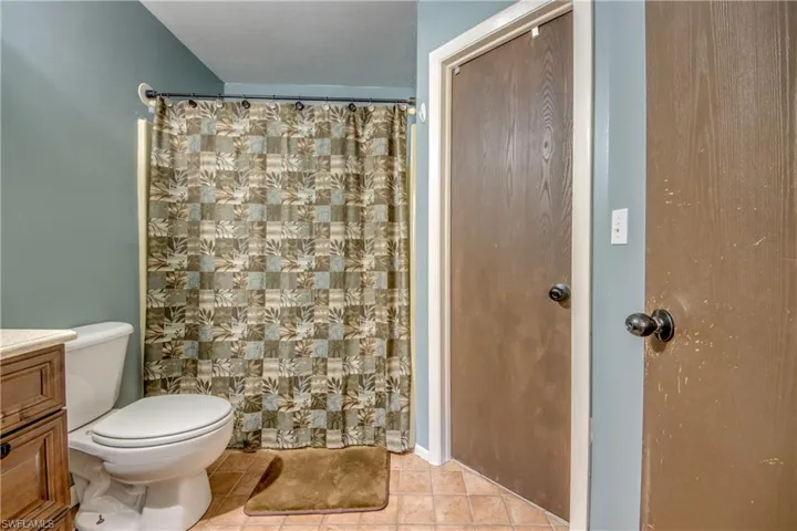 Bathroom with a shower with shower curtain, toilet, vanity, and tile patterned flooring
