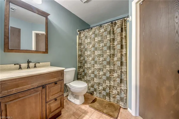 Full bathroom featuring toilet, vanity, tile patterned flooring, and a shower with curtain