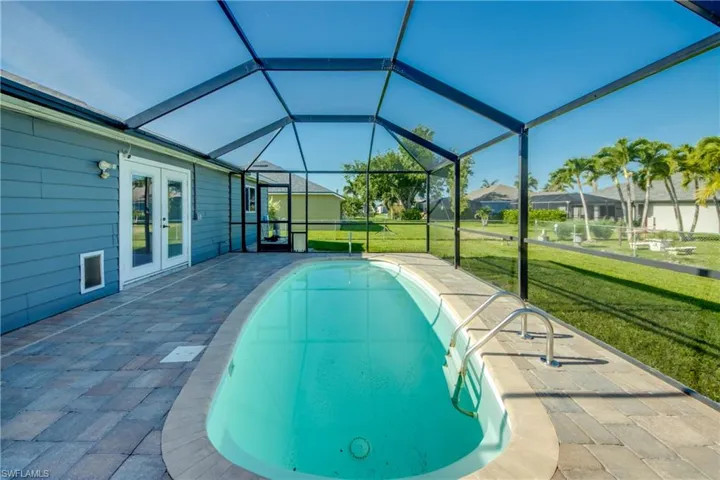 Outdoor pool featuring a lawn, french doors, a patio, and glass enclosure