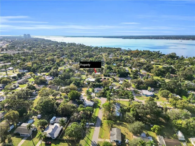 Aerial view of property and surrounding area featuring nearby suburban area and a large body of water