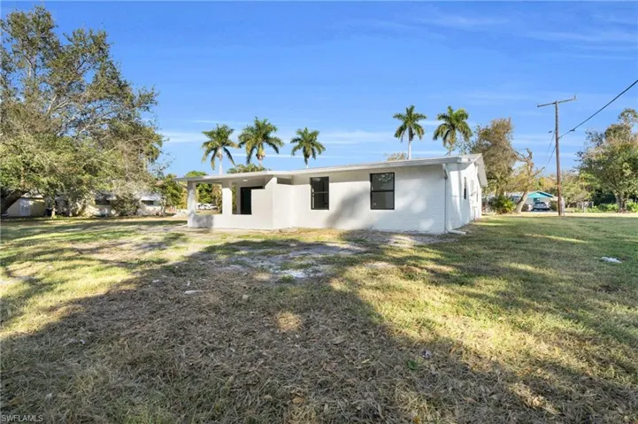 View of side of home featuring a lawn, stucco siding, and a patio