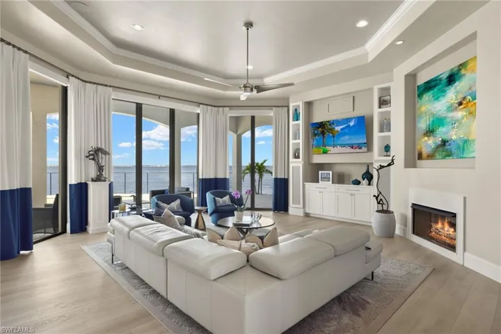 Living room featuring a raised ceiling, light hardwood / wood-style flooring, ceiling fan, and ornamental molding
