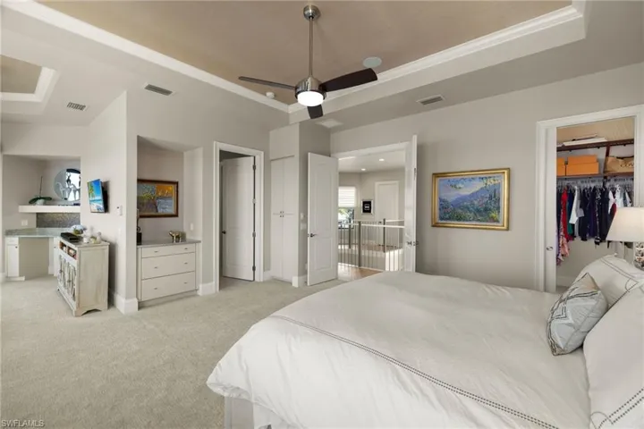 Bedroom featuring light carpet, a tray ceiling, ceiling fan, and ornamental molding