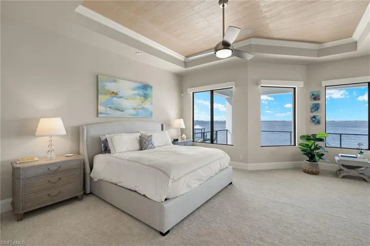 Carpeted bedroom with a water view, a raised ceiling, ceiling fan, and wood ceiling