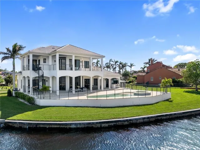 Back of house with a lawn, a water view, a fenced in pool, and a balcony