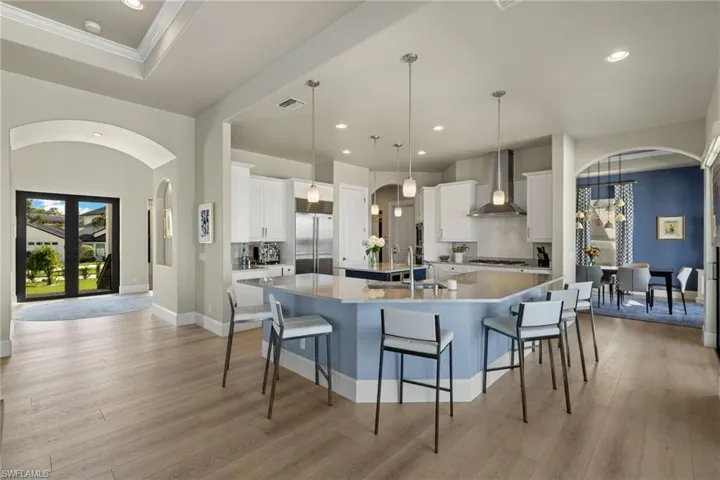 Kitchen with built in fridge, white cabinetry, a spacious island, and wall chimney exhaust hood