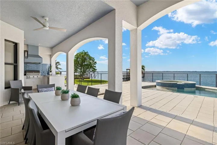 View of patio / terrace featuring an outdoor kitchen, area for grilling, ceiling fan, a swimming pool with hot tub, and a water view