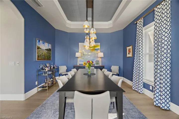 Dining space featuring wood-type flooring, crown molding, and a tray ceiling