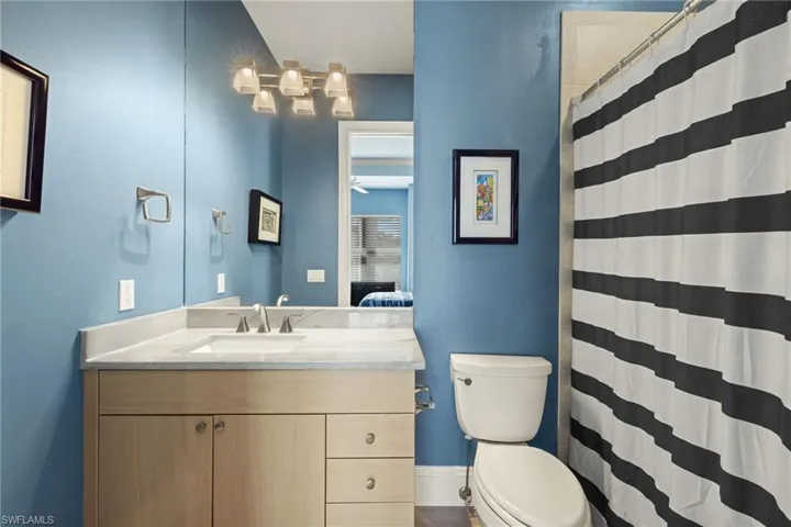 Bathroom with ceiling fan, vanity, a shower with shower curtain, and toilet