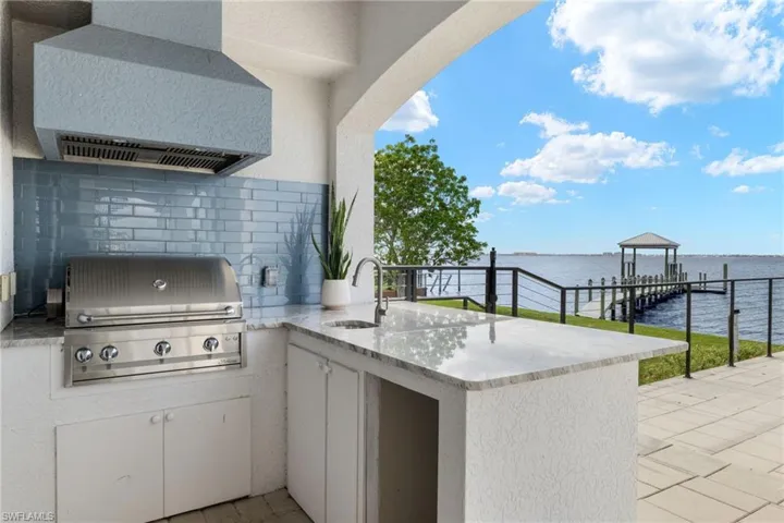 View of patio featuring grilling area, area for grilling, a water view, and a wet bar