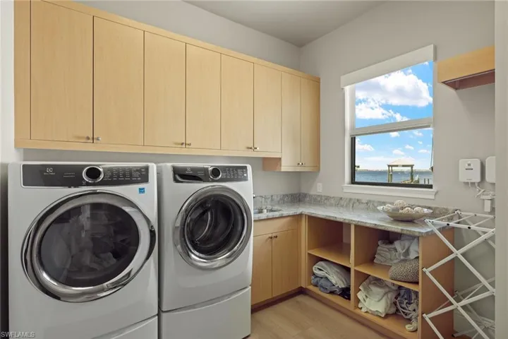 Clothes washing area with cabinets, light hardwood / wood-style floors, and separate washer and dryer