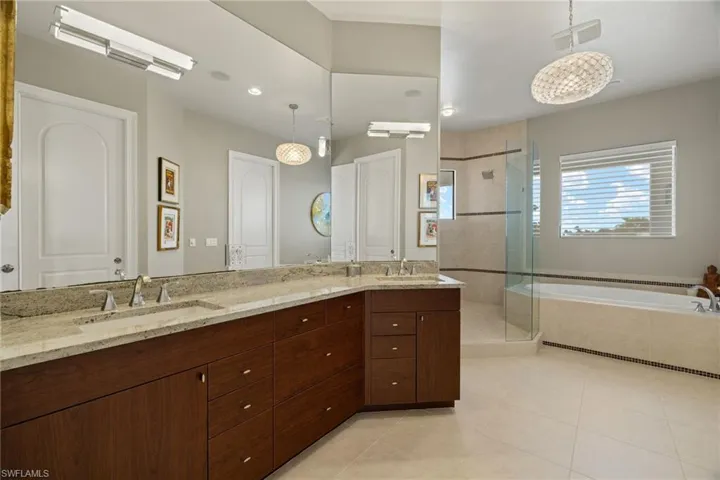 Bathroom featuring tile patterned flooring, vanity, an inviting chandelier, and independent shower and bath