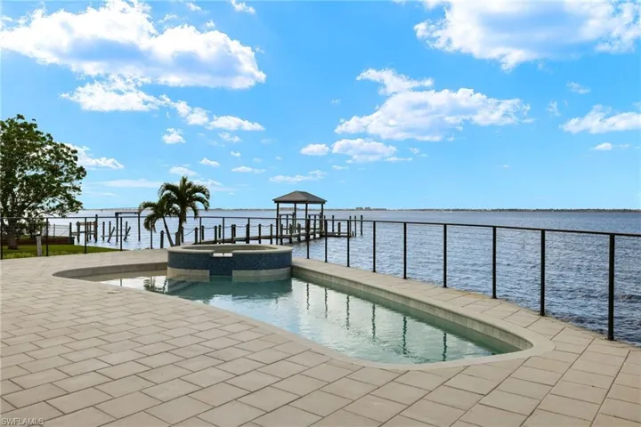 View of swimming pool with a water view and a dock