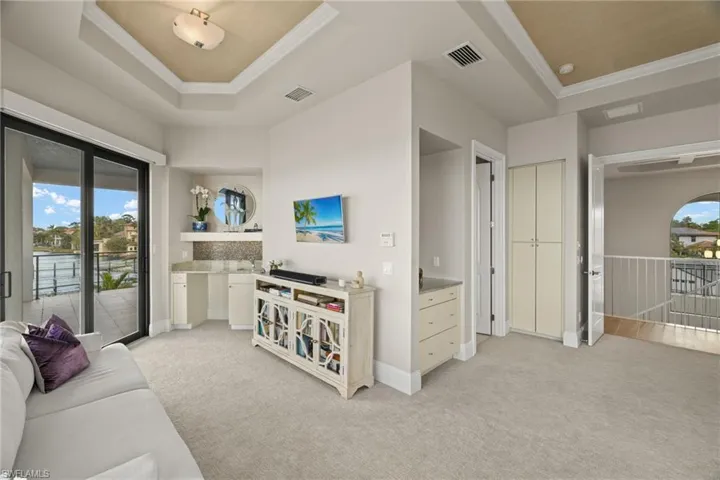 Carpeted living room featuring a tray ceiling and ornamental molding