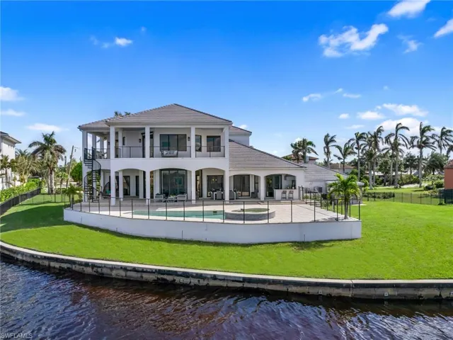 Rear view of house with a lawn, a balcony, a water view, and a patio