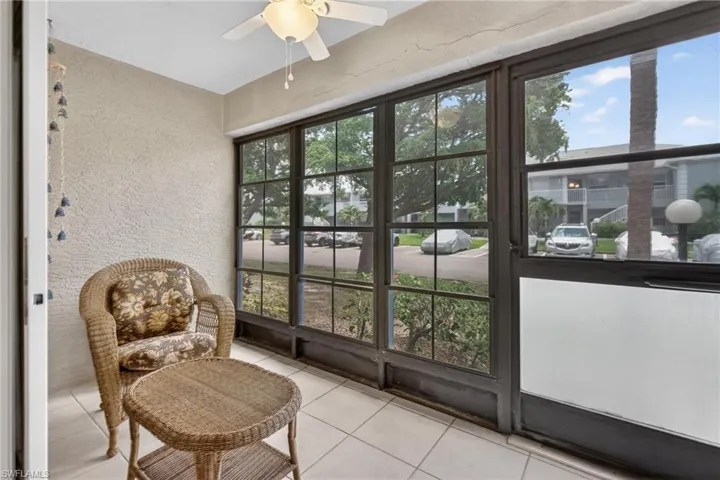 Screened-in porch featuring full-length windows with dark frames, a white ceiling fan, textured walls, and tiled flooring