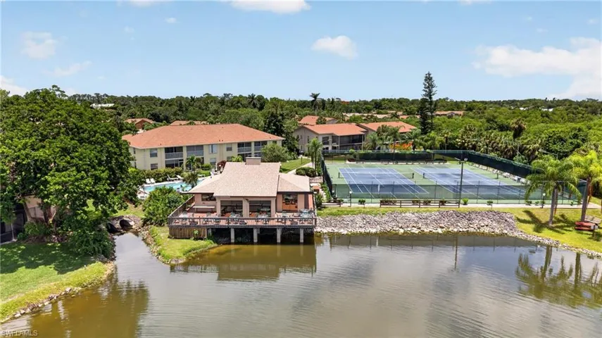 Waterfront clubhouse with an expansive outdoor deck, multiple tennis courts, and a swimming pool
