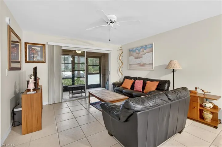 Open-concept living space with light-toned tile flooring, neutral wall paint, and a white ceiling fan