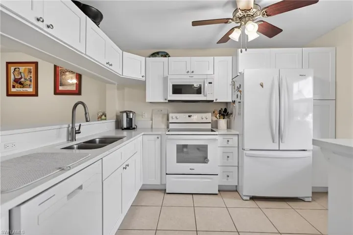 Kitchen featuring white cabinetry, white countertops, stainless steel sink with gooseneck faucet, white appliances, and tile flooring