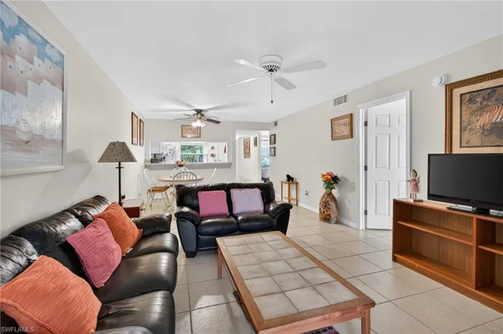 Spacious living area featuring light-toned tile flooring, light-colored walls, and a ceiling fan