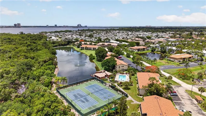 Aerial perspective showcasing a community with tennis courts and a swimming pool