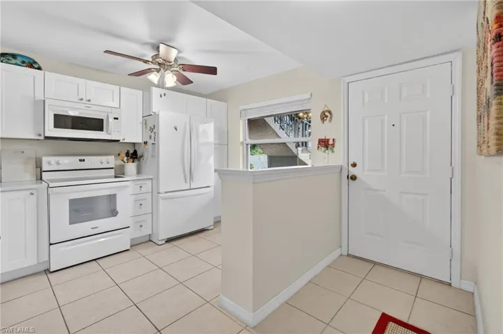 Kitchen featuring white cabinetry, white appliances, a ceiling fan, and tile flooring