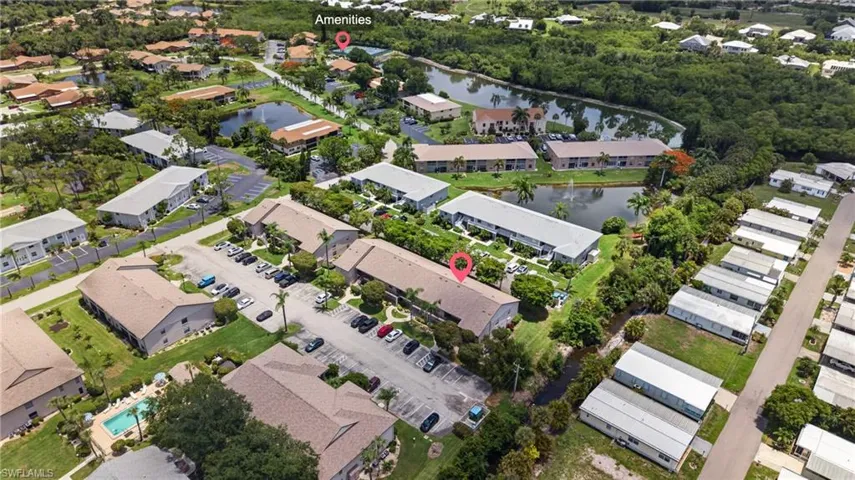 Aerial view of a community featuring multi-unit residences, extensive parking areas, and mature landscaping