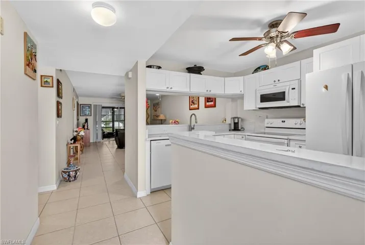 Bright kitchen featuring white cabinetry, a built-in microwave, white appliances, and a ceiling fan