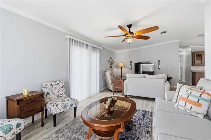 Living room featuring crown molding, wood finished floors, and a ceiling fan