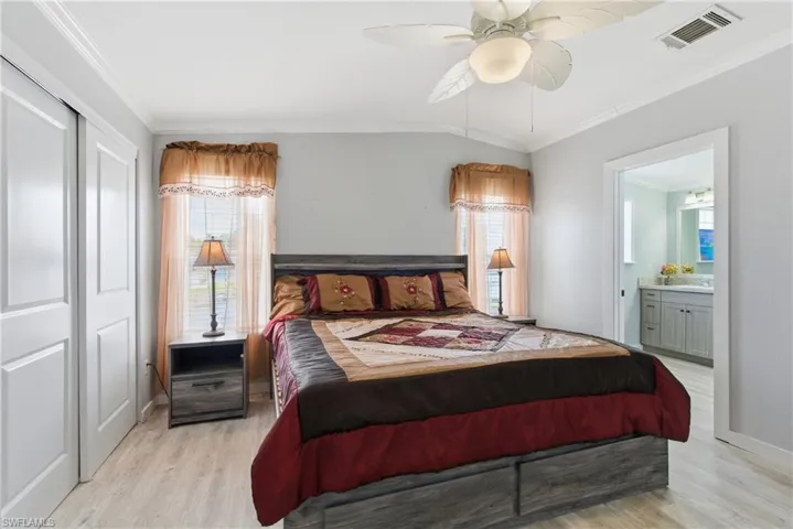 Bedroom with crown molding, multiple windows, a closet, light wood finished floors, and a ceiling fan