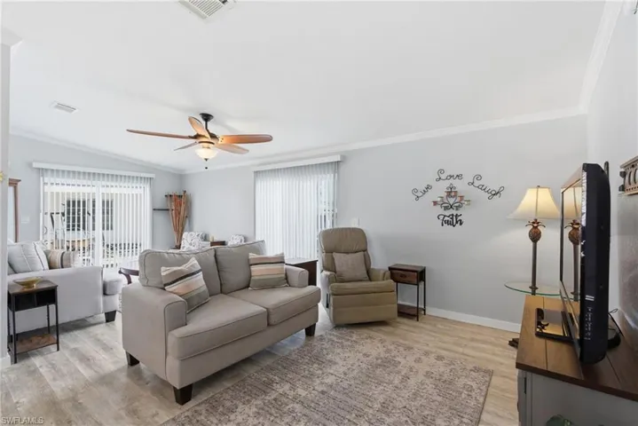 Living area with ornamental molding, light wood finished floors, ceiling fan, and plenty of natural light