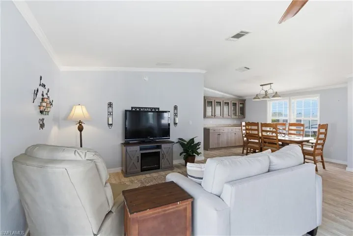 Living room with crown molding, vaulted ceiling, and light wood-type flooring