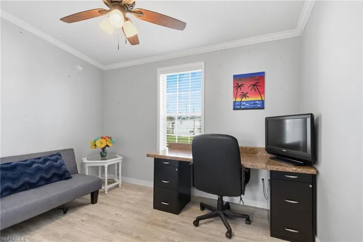 Office space with light wood-type flooring, ornamental molding, and a ceiling fan