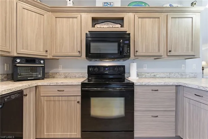 Kitchen featuring black appliances, light brown cabinets, and light countertops