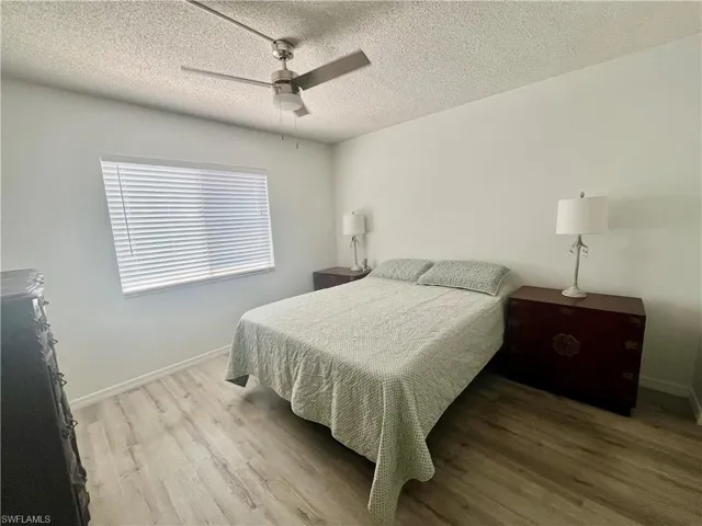Bedroom with a ceiling fan, light wood-type flooring, and a textured ceiling