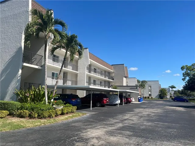 View of apartment building / complex featuring covered parking