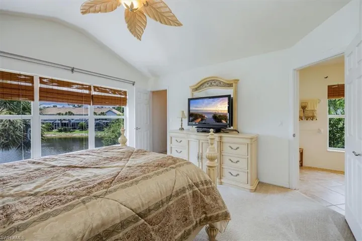 Bedroom with vaulted ceiling, light colored carpet, and ceiling fan