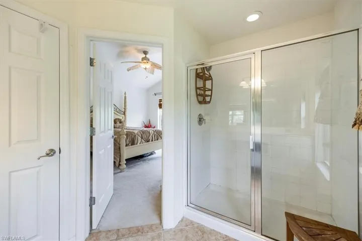 Full bath featuring connected bathroom, ceiling fan, a shower stall, lofted ceiling, and recessed lighting