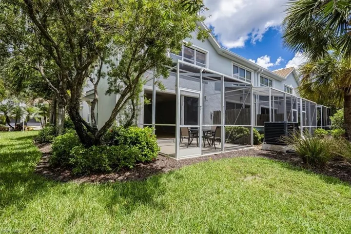 Rear view of property with a lawn, a patio, stucco siding, and glass enclosure